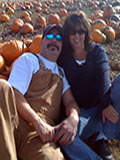 picture of owners in a pumpking patch, embracing